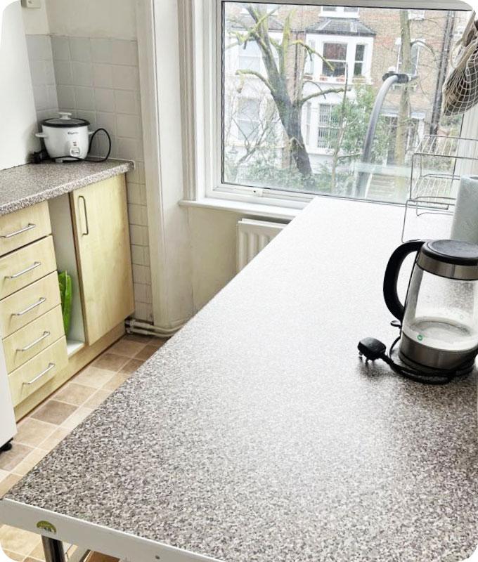 An image of a pristine and well-organized kitchen countertop after decluttering and cleaning. The countertop is clear of any items, and all appliances, cutting boards, and kitchen items are neatly arranged. The surface is sparkling clean, free from any spills, stains, or debris. The countertop exudes a sense of cleanliness and order, with a visually pleasing appearance.